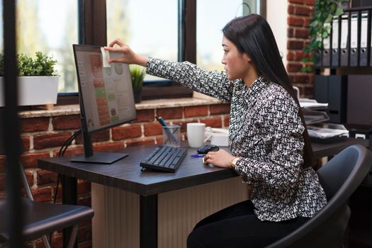Marketing company recruiter sticking potential customer contact note on work computer screen