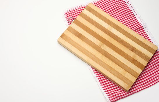 empty rectangular wooden kitchen cutting board and red towel in a white cage on a white table, top view