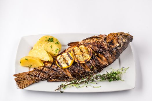 Grilled carp fish with rosemary potatoes and lemon, close up