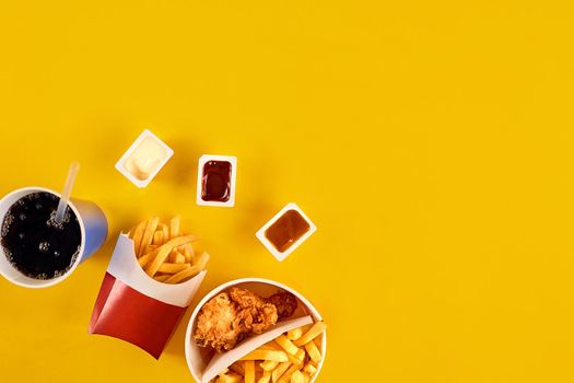 Fast food concept with greasy fried restaurant take out as onion rings, burger, fried chicken and french fries as a symbol of diet temptation resulting in unhealthy nutrition.
