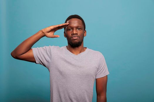 Young man doing military salute with hand over forehead