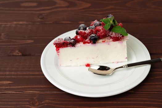 Piece of berry cheesecake served on brown wooden table