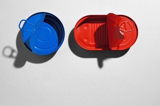 Red and blue painted tin cans on gray background