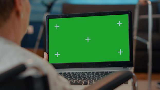 Elder person with disability using green screen on laptop
