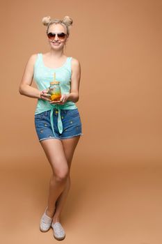 A beautiful woman in a bright outfit, denim shorts in the studio. Summer