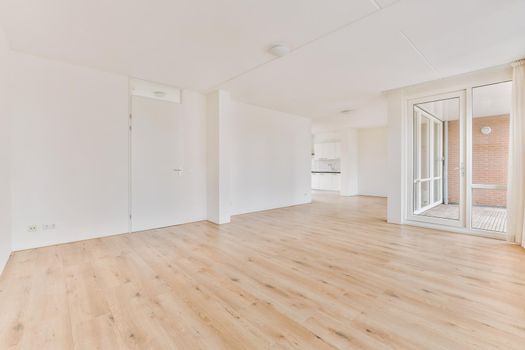 Spacious bright empty room with access to the glazed balcony