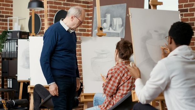 Elder teacher guiding young student to draw vase sketch