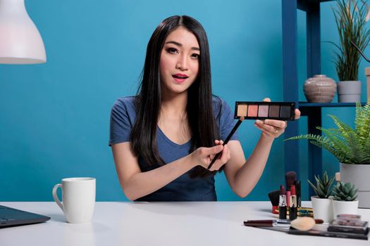 Asian woman influencer holding palette showing at camera