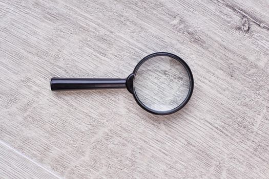 Magnifying glass on wooden backdrop.