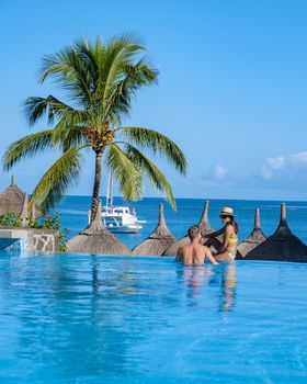 Beautiful tropical beach front hotel resort with swimming pool, sun-loungers and palm trees during a warm sunny day, paradise destination for vacations