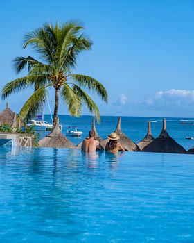 Beautiful tropical beach front hotel resort with swimming pool, sun-loungers and palm trees during a warm sunny day, paradise destination for vacations