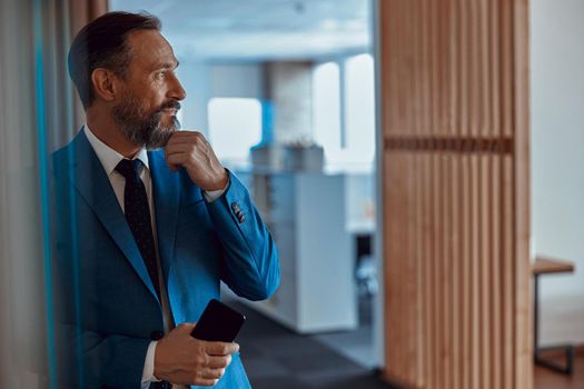 Adult bearded businessman looking away thoughtfully in office