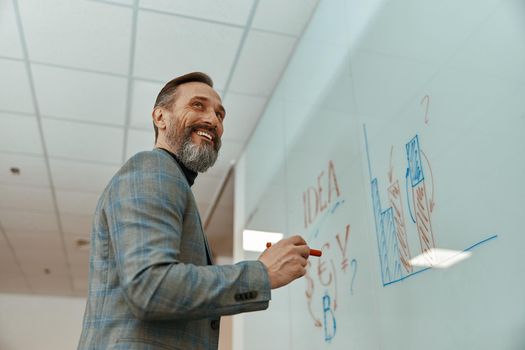 Smiling Caucasian man using whiteboard for his presentation