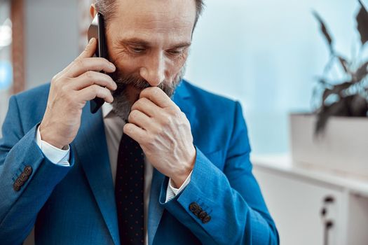 Close up of pensive bearded man talking on smartphone