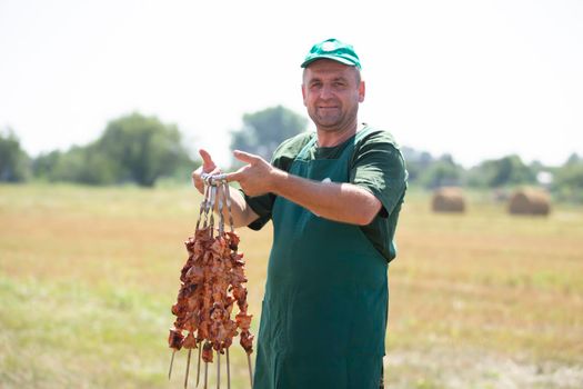 A man holds a skewer with a shish kebab.