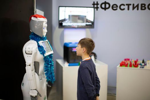 Boy talking, playing with android robot at the exhibition