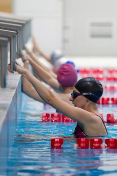 Women swimmers in a swimming hat and goggles on the background of the pool.
