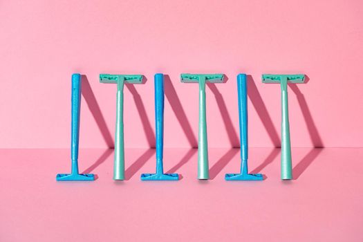 Female disposable razors on pink background, studio shot