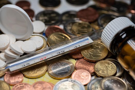 Medicine and fever thermometer on Euro coins and Money. Cash money and health medicine.