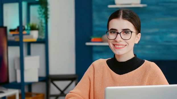 Portrait of smiling person sitting at desk and using laptop