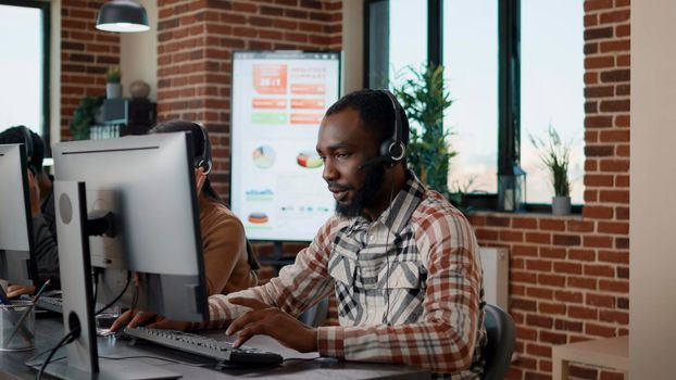 Young man using headphones at call center to help people