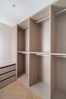 New built-in furniture in a small dressing room. Modern and empty storage room with wardrobe, drawers and plenty of space for hangers.