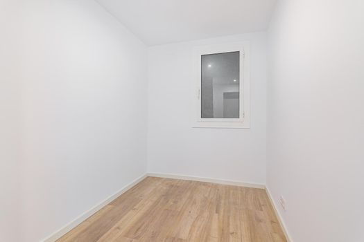 Empty room after renovation with white walls and dust window without natural light. Typical apartment in Barcelona