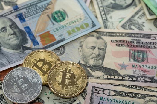 Bitcoin coins on Dollar Banknotes, fifty and hundred Dollar bills. US Currency and BTC Crypto currency