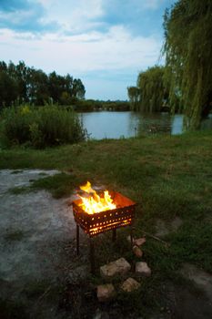 evening-burning firewood in the grill, preparation for the frying of meat, near the lake