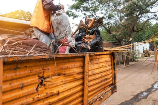 A municipal worker collecting garbage on top of a truck in a poor community in Managua, Nicaragua. Concept of solid waste management in Central America
