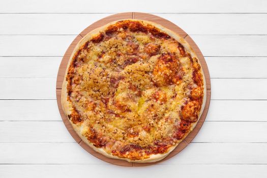 Whole round pizza topped with cheese and oregano on wooden plate. Top view on white board background