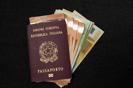 Italian Passport filled with Euro Banknotes on Dark Background. Travel ID and Cash Money. Travel Funds, fifty, hundred and two hundred Euros for Europe Vacation