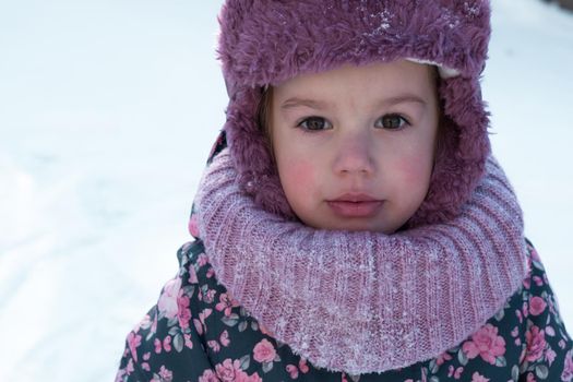 Winter, family, childhood concepts - close-up portrait authentic little preschool minor 3-4 years girl in pink hat look at camera posing smile in snowy frosty weather. happy kid face have fun outdoors