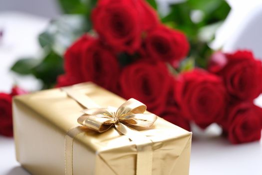 Golden giftbox and bouquet of red roses
