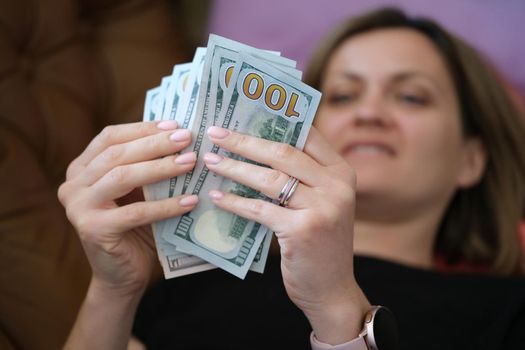 Happy smiling woman counting money at home