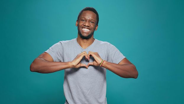 Smiling man making heart shape sign with hands in front of camera