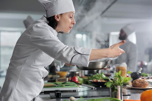 Food industry worker stirring in pan delicious food while preparing ingredients for meal recipe in restaurant professional kitchen.