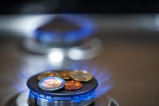 Euro coins on top of gas cooker. Gas stove burning expensive natural gas