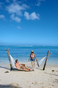 tropical beach with hammock in the ocean, white sandy beach with hammock Le Morne beach Mauritius, couple men and women in hammock