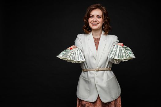 Cute young girl shows a lot of money in the hands, picture isolated on black background