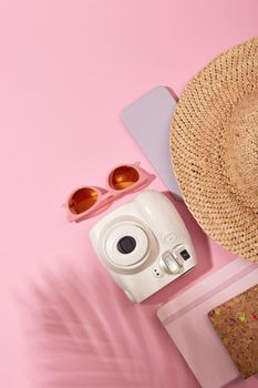 Instant camera near sunglasses and hat pink