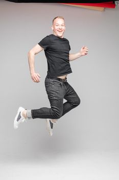 funny man jumps and rejoices in studio on white background, backstage of a photosession