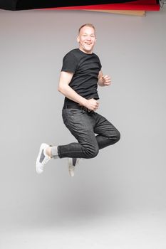 funny man jumps and rejoices in studio on white background, backstage of a photosession