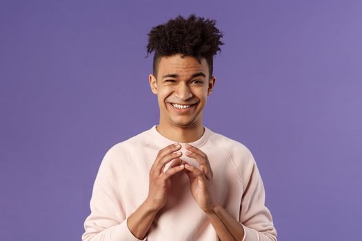 Portrait of creative young smart man with dreads, steeple fingers near chest and smirk devious, have perfect plan, scheming something for april fools day, standing purple background sly