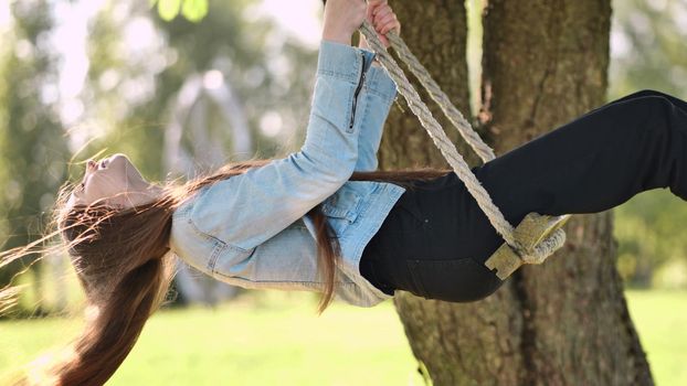 Young beautiful long-haired girl on a rope swing.
