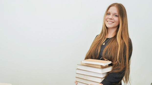A schoolgirl in a good mood with a pile of books.