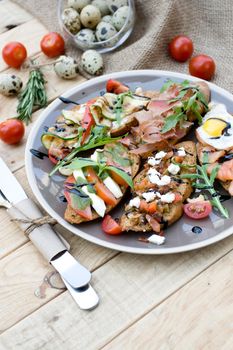 Many delicious bruschetta with cheese, tomato, quail egg, ham, salmon, roasted vegetables and herbs