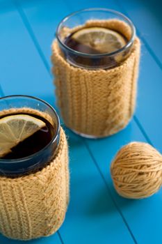 Two cups of tea in yellow Knitted sweaters on blue background
