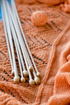 Many wooden spokes lie on an orange knitted plaid