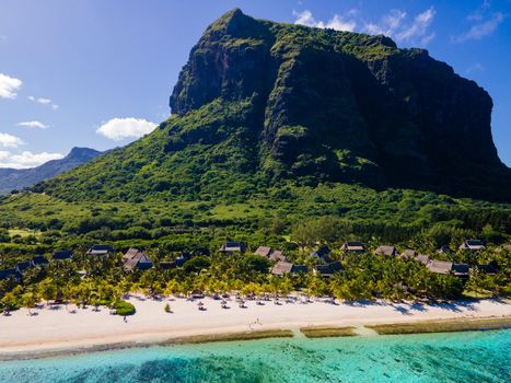 Le Morne beach Mauritius,Tropical beach with palm trees and white sand blue ocean and beach beds with umbrella,Sun chairs and parasol under a palm tree at a tropical beac, Le Morne beach Mauritius